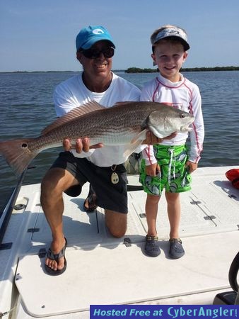 Capt. Joe Porcelli helps Wade hold up his big redfish.